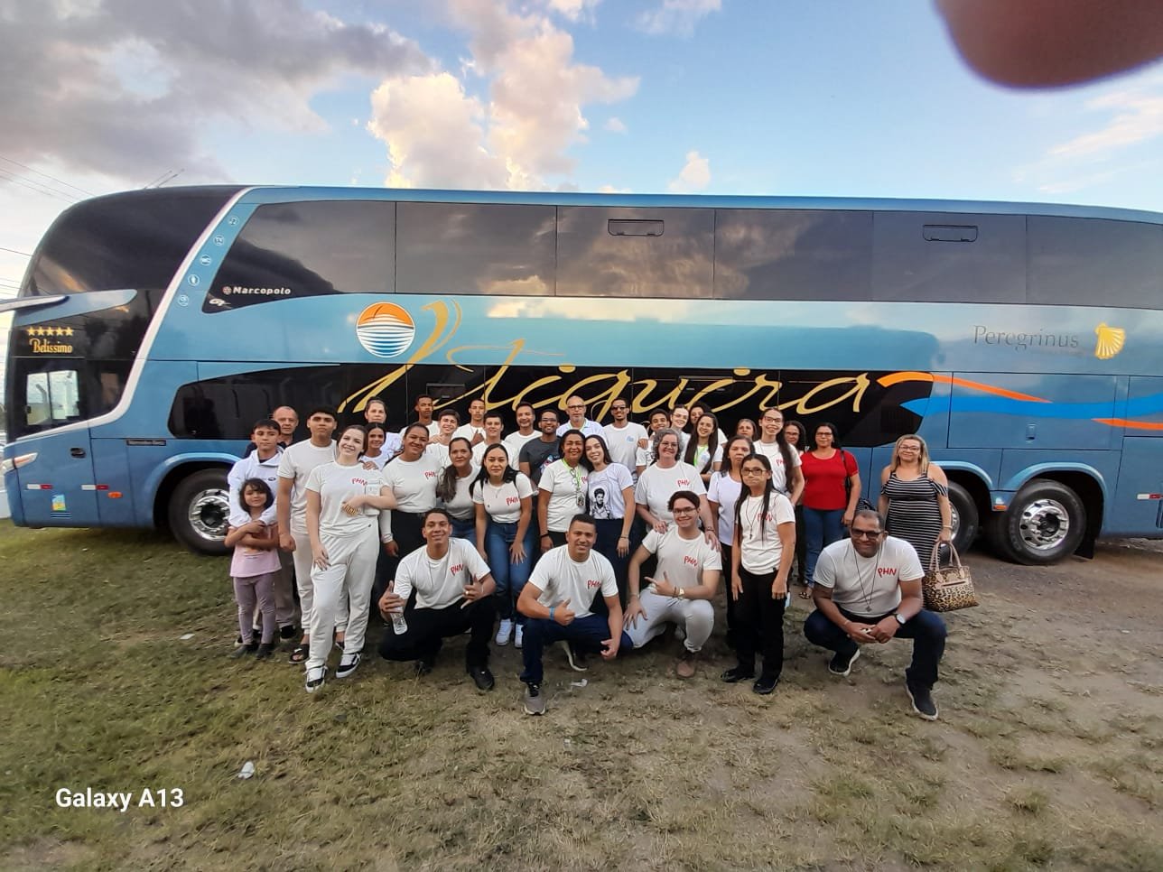 Peregrinos em frente ao ônibus de dois andares da caravana, ao entardecer